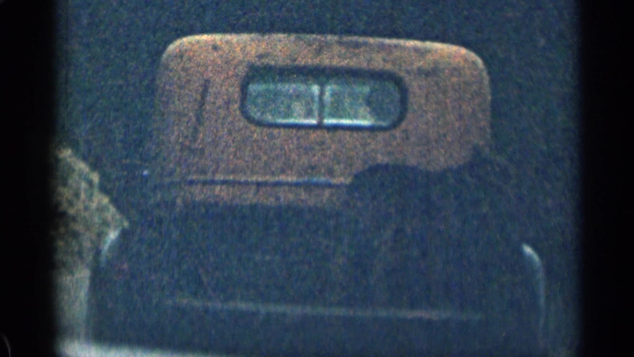 1963 Colorado 8mm frame showing the rear of a vehicle with a small window, partially obscured by dark exposure and film grain.
