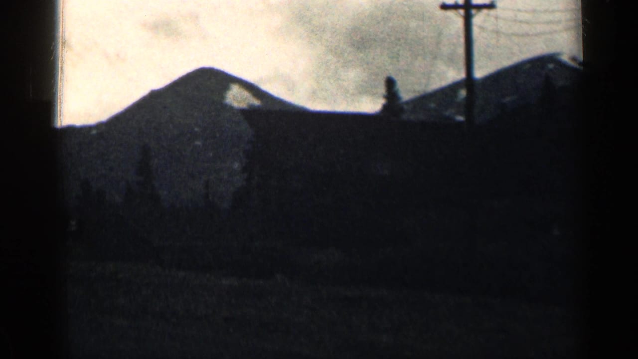 Shadowed roofline or building below a mountain ridge and utility pole.