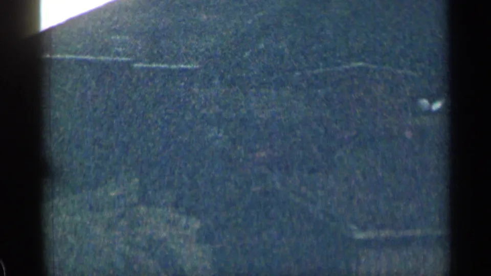 Low-light 1963 Colorado 8mm frame showing a dark textured exterior field with faint horizontal lines and heavy film grain.
