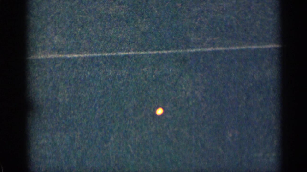 Low-light 1963 Colorado home-movie frame with a small orange light floating against a dark blue-green exterior background.