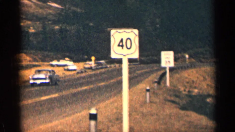 1963 Colorado road scene with cars, a visible U.S. Route 40 sign, and mountain terrain nearby.