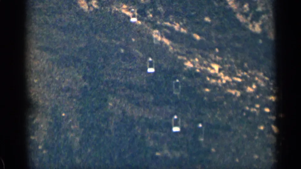 1963 Colorado 8mm frame showing a dark wooded hillside with small bright patches that may be lingering snow.