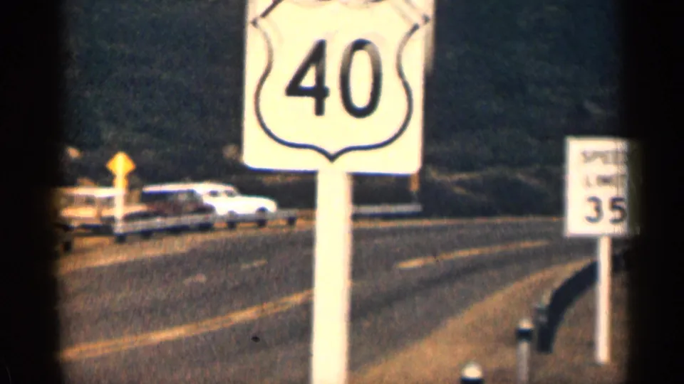 1963 Colorado roadside frame with a U.S. Route 40 shield, speed limit 35 sign, pavement, and mid-century cars in the background.