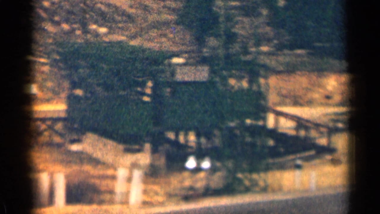 Roadside area with a wooden structure and a parked vehicle near trees.