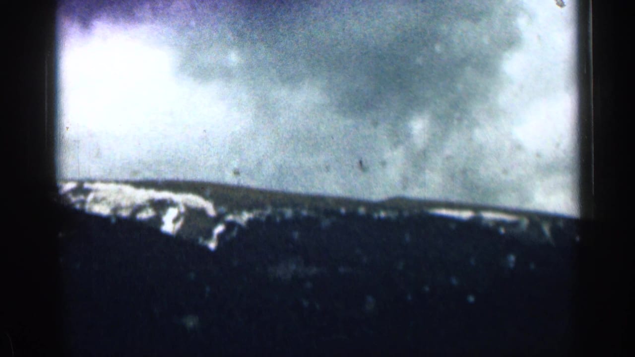 1963 Colorado mountain view on 8mm film, with snow patches along a dark ridge under cloudy sky.