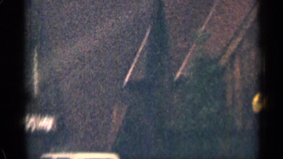 Roadside lodge sign in 1963 Colorado home-movie footage, with Pioneer S-V Lodge lettering visible through blur and grain.