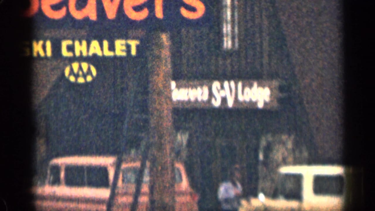 Blurred motel sign with Beaver's Ski Chalet lettering and parked vehicles below.