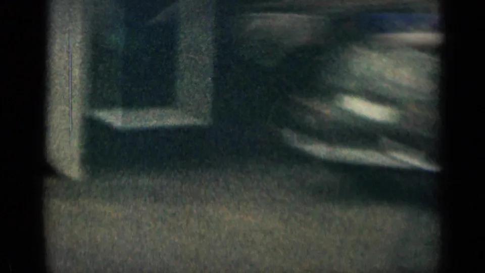 Grainy 1963 Colorado frame showing a light blue van or wagon near a stairway outside a roadside building.