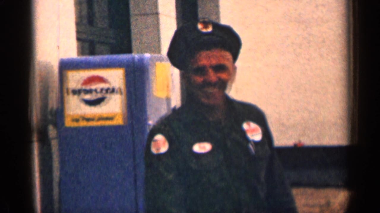 Uniformed man smiling beside a blue Pepsi-Cola vending machine.