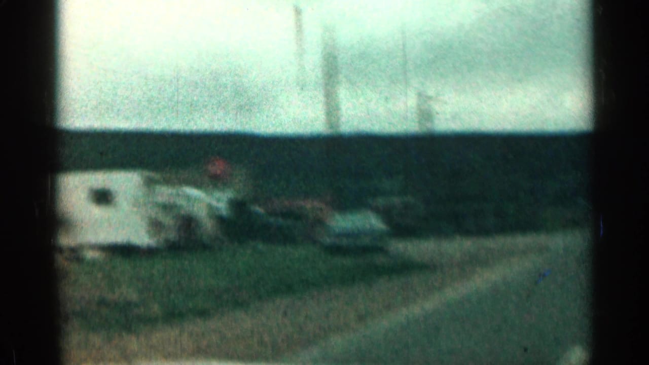 Faded 1963 Colorado road frame with a blurred parked vehicle or trailer shape, open horizon, and dark film-frame bars.