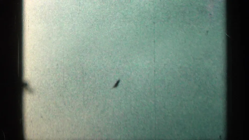 Pale green 8mm end frame with no clear subject, visible scratches, dust, uneven exposure, and dark film borders.