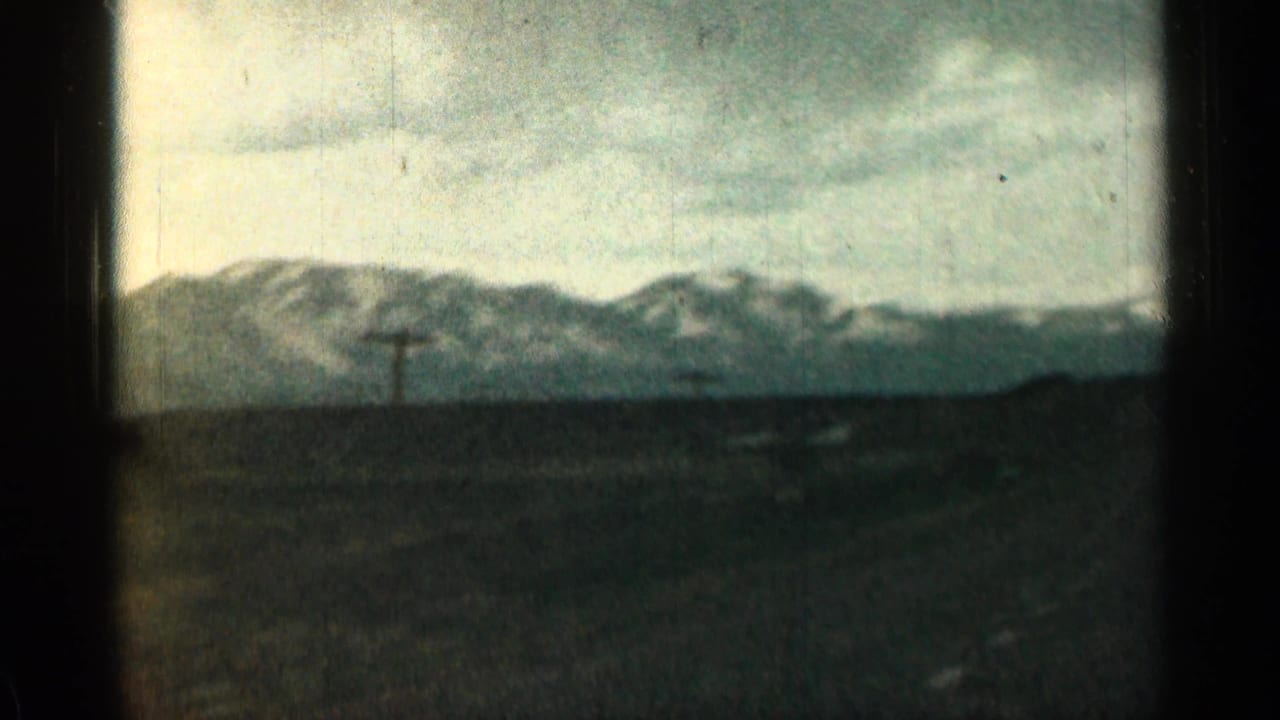 Distant mountains and utility poles seen beyond a vehicle window.