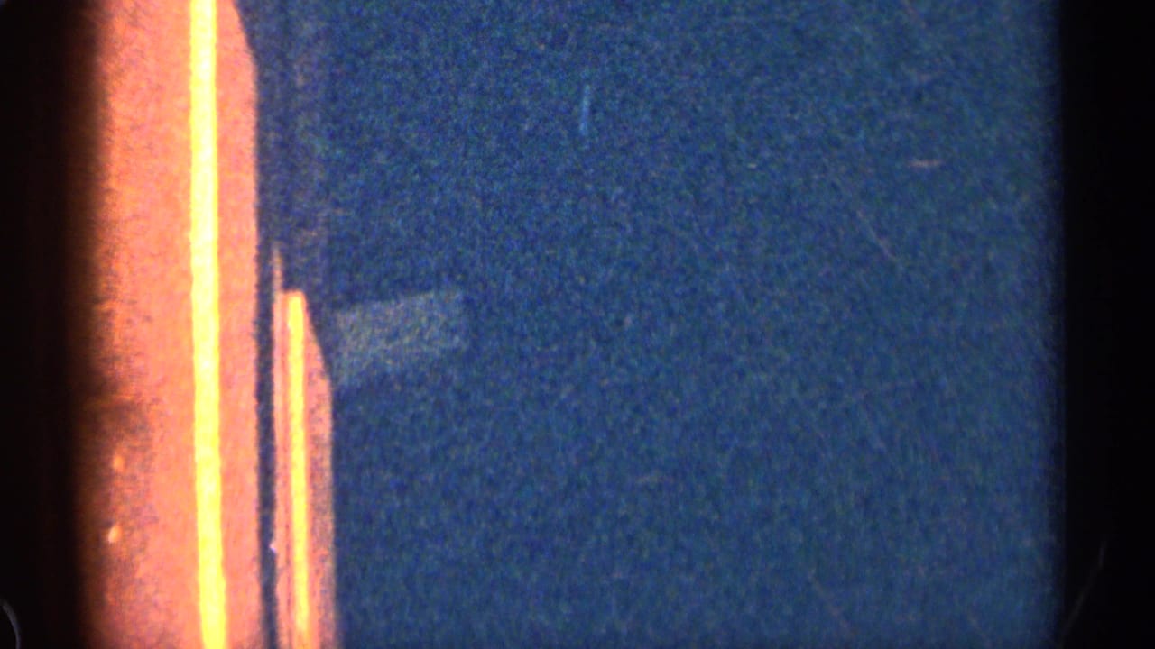 1963 8mm frame showing a mostly blue, out-of-focus exposure area with orange film edge flare and visible grain.