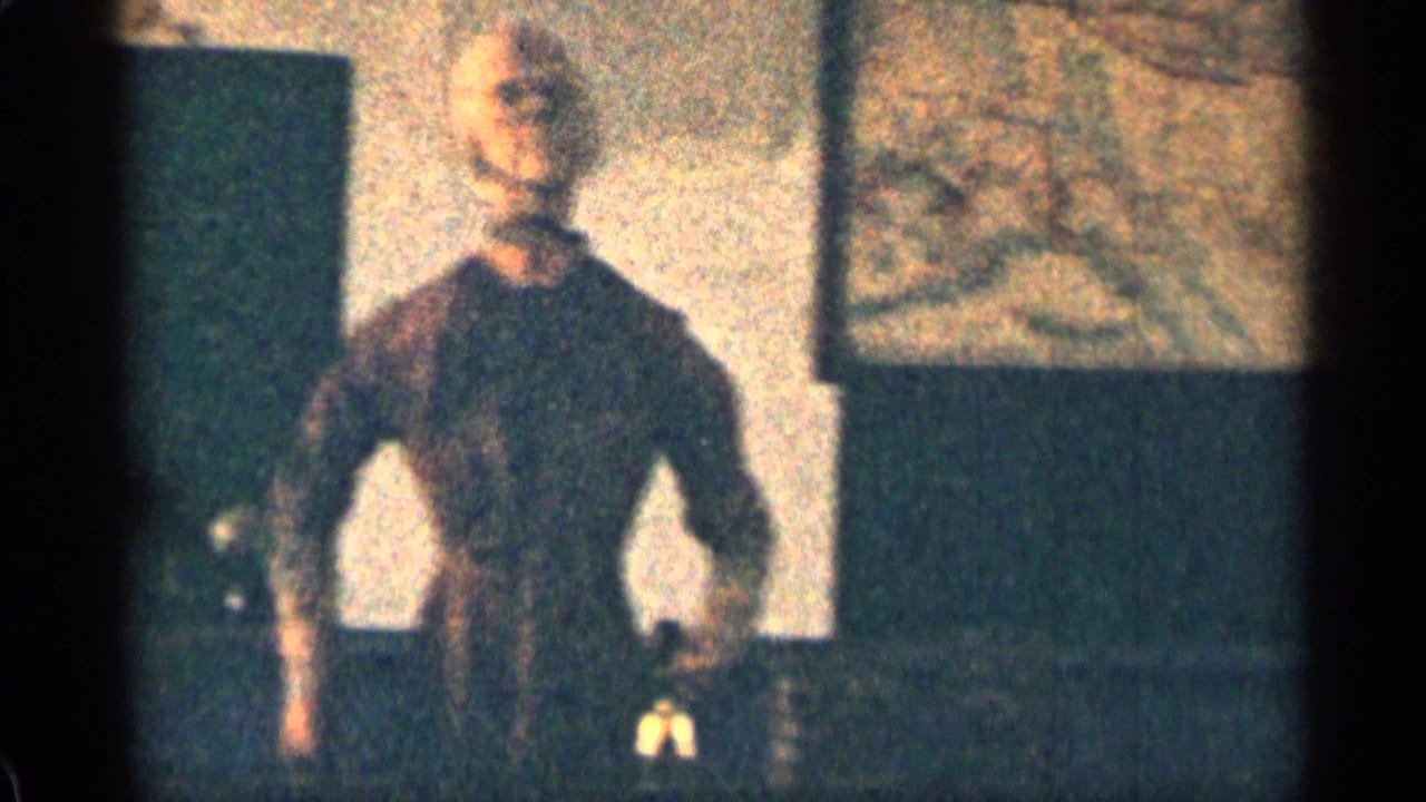Adult figure in dark clothing standing near a wall or doorway beside a wooden exterior.