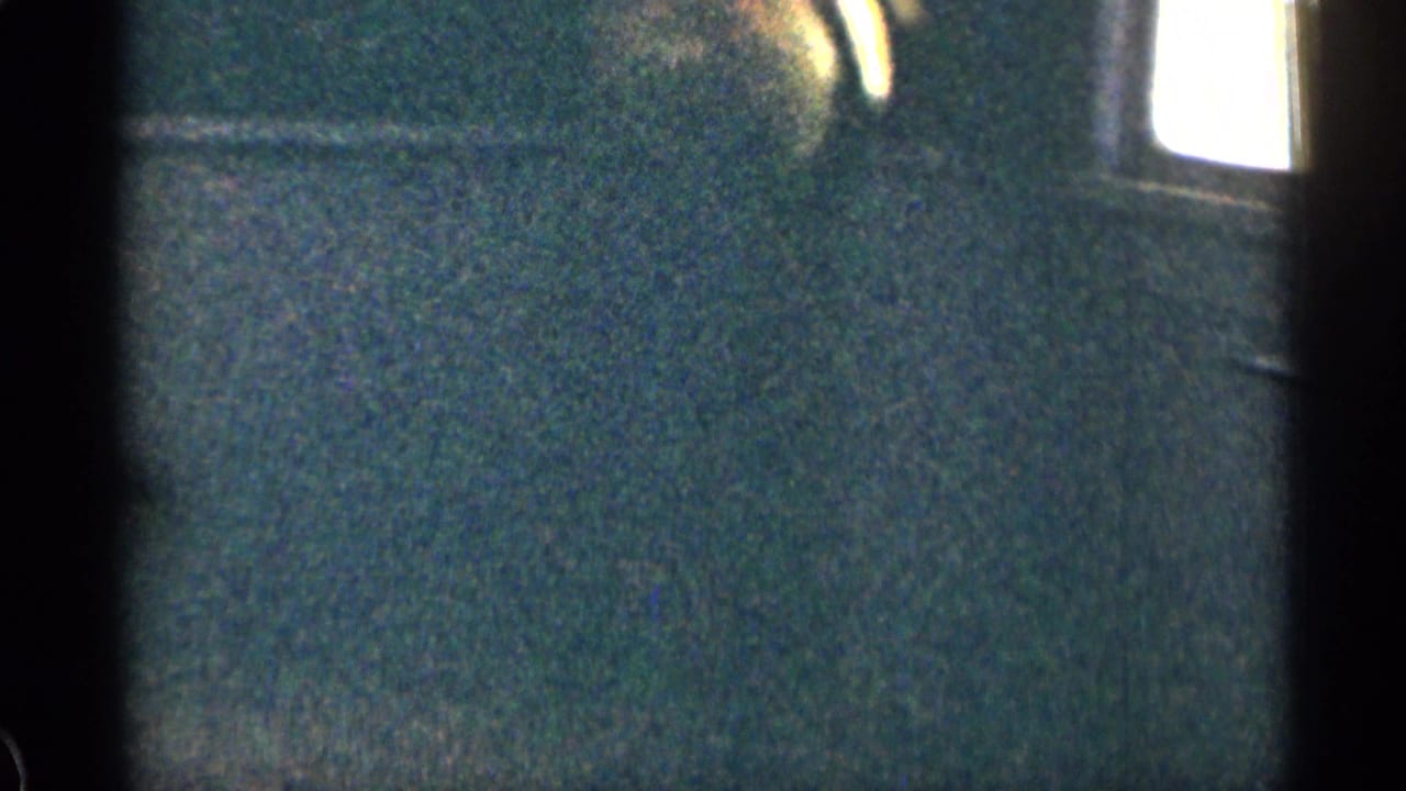 Dark, grainy view of a building wall or shaded exterior with bright window area at the edge.