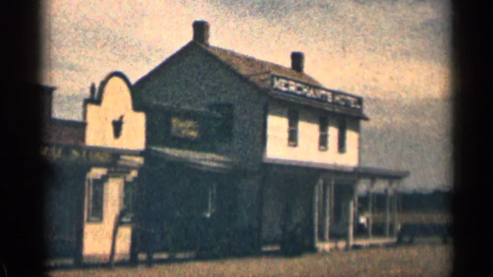 1963 Colorado 8mm view of an arched storefront entrance and adjoining hotel building with porch roof and balcony rail detail.