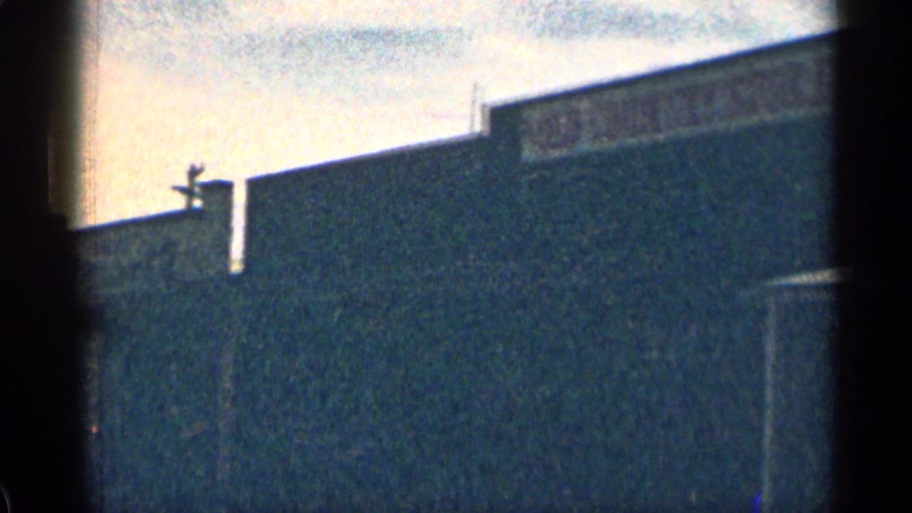 Backlit building wall and roofline with dark vertical film edge.