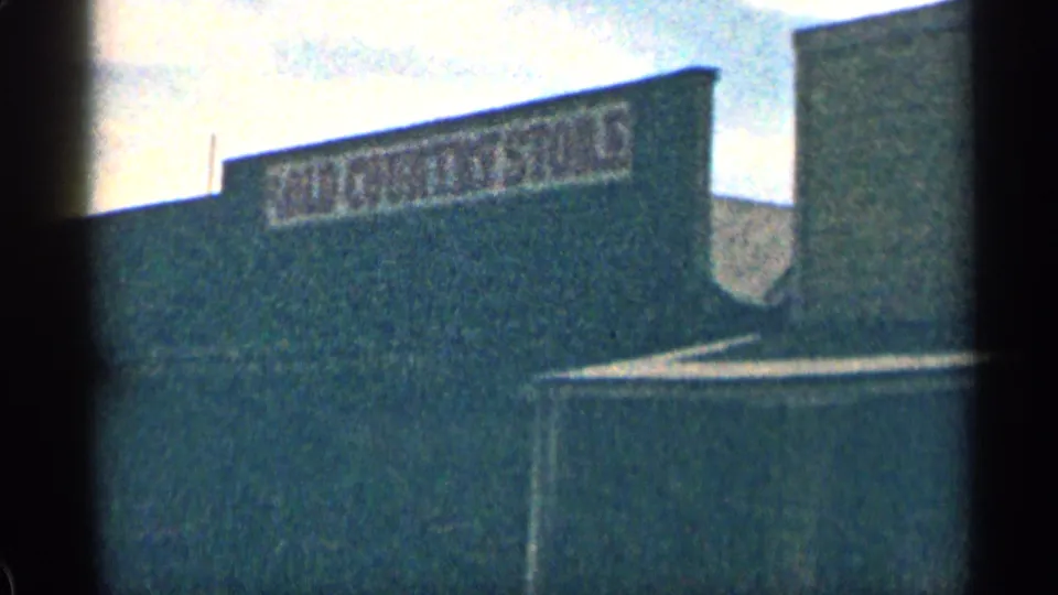 1963 Colorado 8mm frame showing a Western-style facade with a faded “OLD COUNTRY STORE” sign above a lower roof.