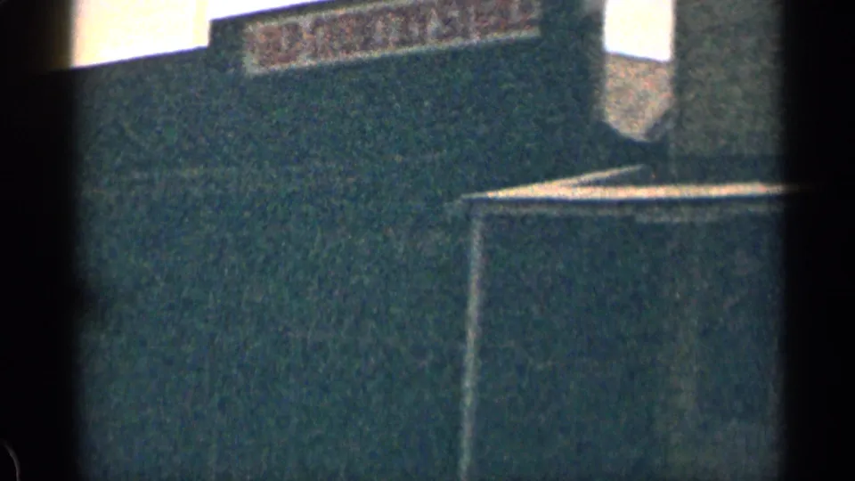 1963 Colorado 8mm view of a dark wooden building with a partial faded sign near the roofline.