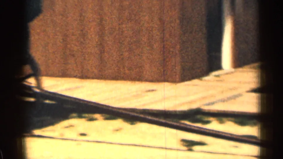 1963 Colorado 8mm frame with a partial wagon wheel, long handle, pale ground, and wooden wall in the background.