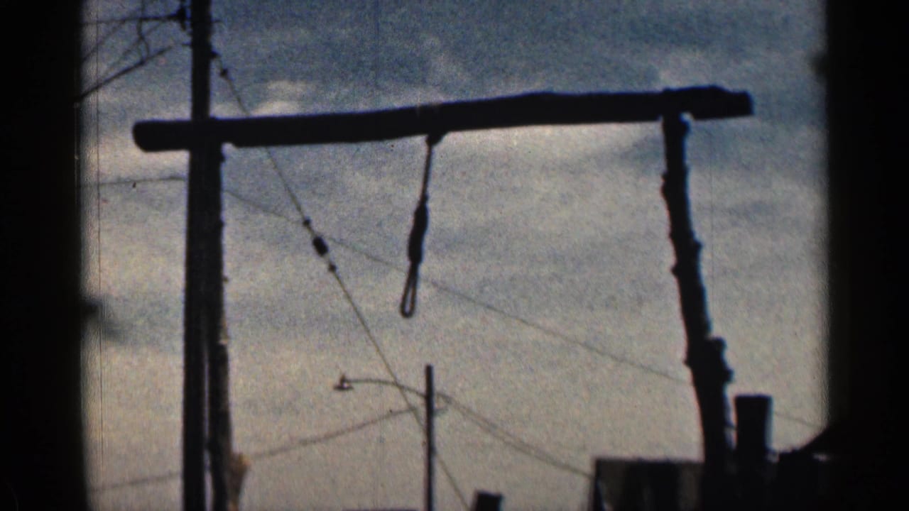 1963 Colorado 8mm frame showing a wooden gallows beam and noose in silhouette, with utility wires behind it.
