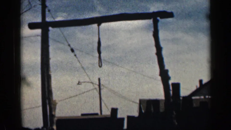 1963 Colorado 8mm frame showing a dark wooden frame or hoist-like structure silhouetted against clouds and utility lines.
