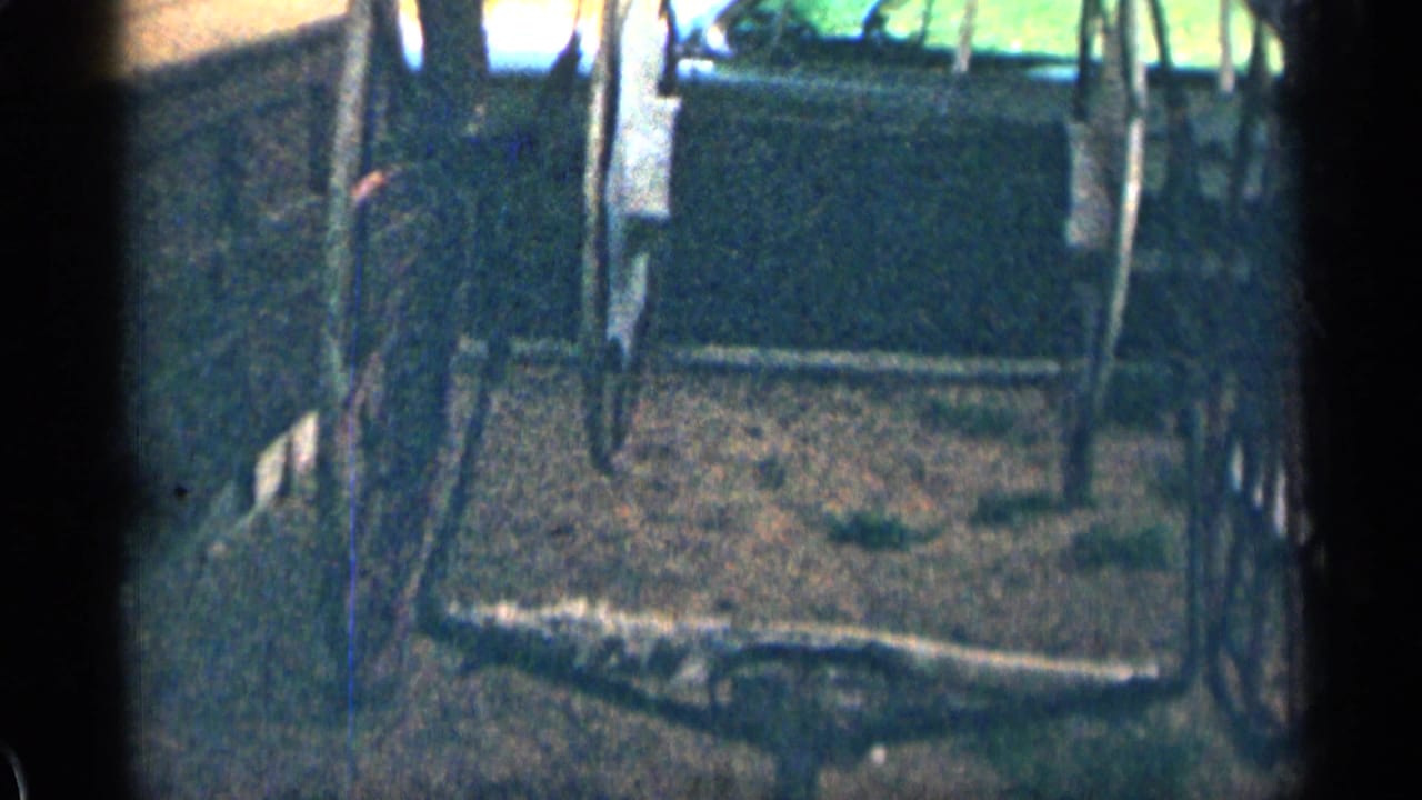 Grainy 8mm view of a rustic wooden cart or wagon set in a narrow outdoor area, likely part of the Colorado home-movie sequence.