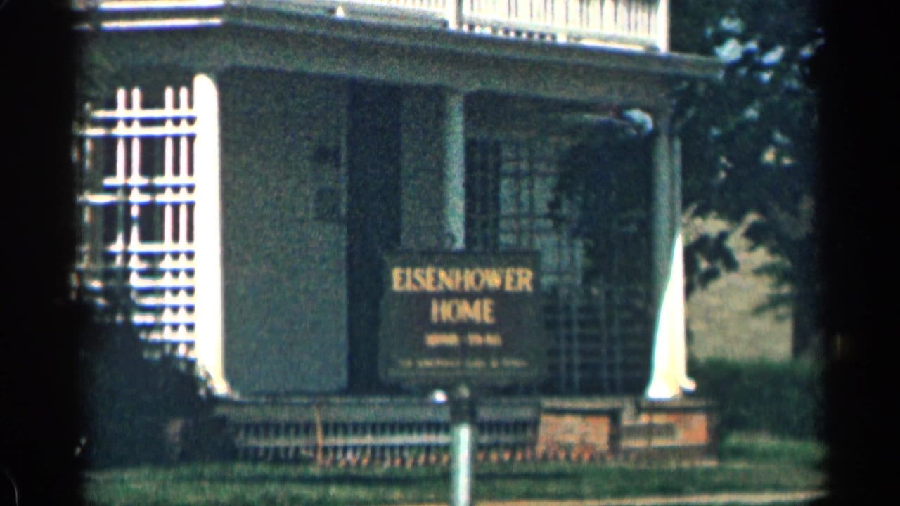 1963 Colorado 8mm frame showing an Eisenhower Home sign outside a porch-front house with white columns and shaded windows.
