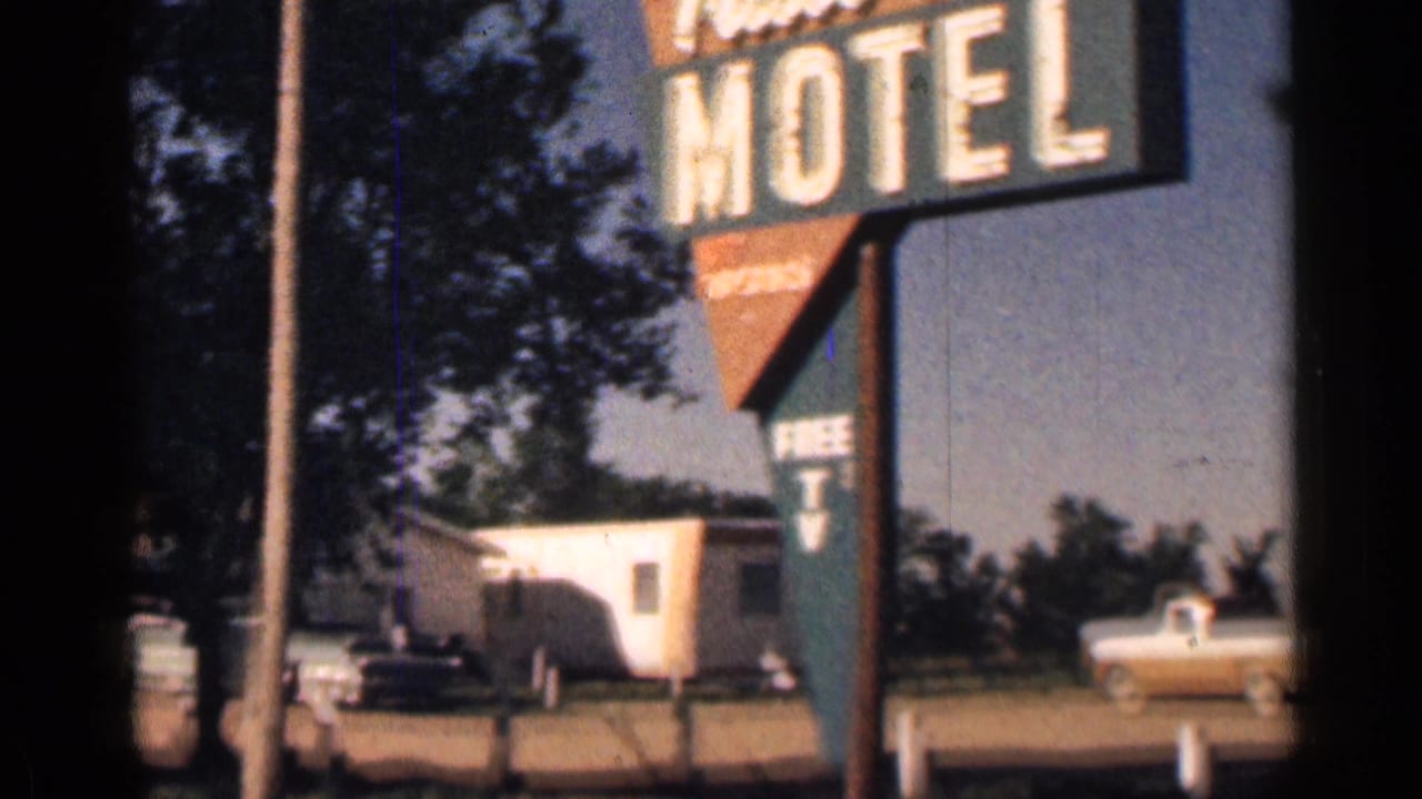 Trail Inn Motel sign beside a roadside lot with cars and small buildings.