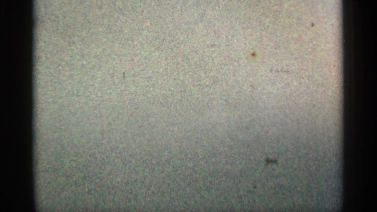 Grainy 8mm frame with dark vertical borders and muted blank leader-like area before the Montgomery label appears.