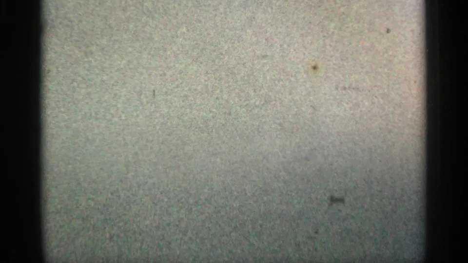 Grainy 8mm frame with dark vertical borders and muted blank leader-like area before the Montgomery label appears.