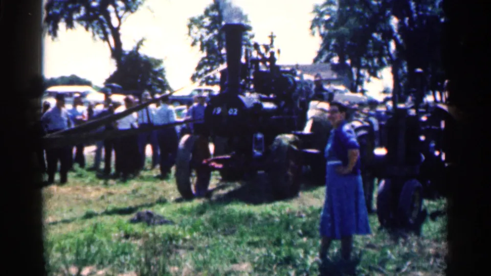 1963 Montgomery, Minnesota footage showing a black steam traction engine with a crowd and a woman in a blue dress nearby.