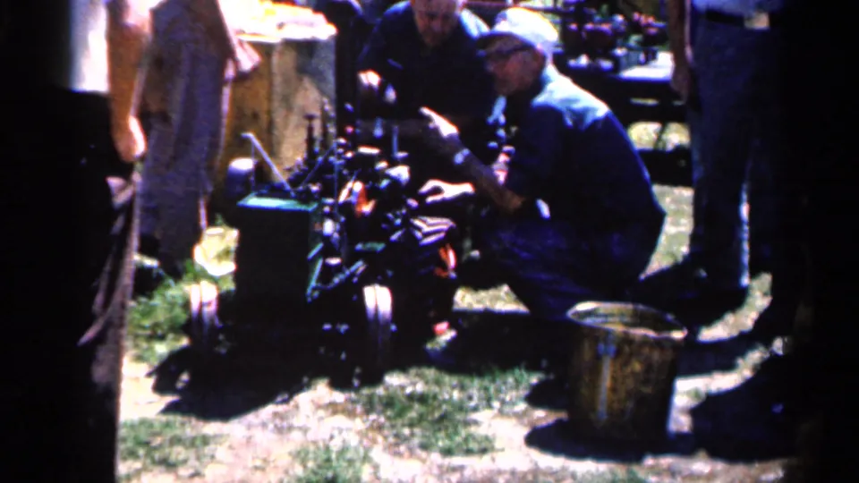 1963 Montgomery, Minnesota frame showing a closer view of people beside farm machinery during the hay harvest workday.
