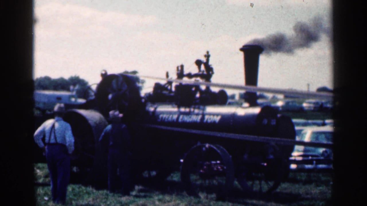 1963 Montgomery, Minnesota 8mm frame of a black steam engine labeled Steam Engine Tom with smoke rising as spectators watch.