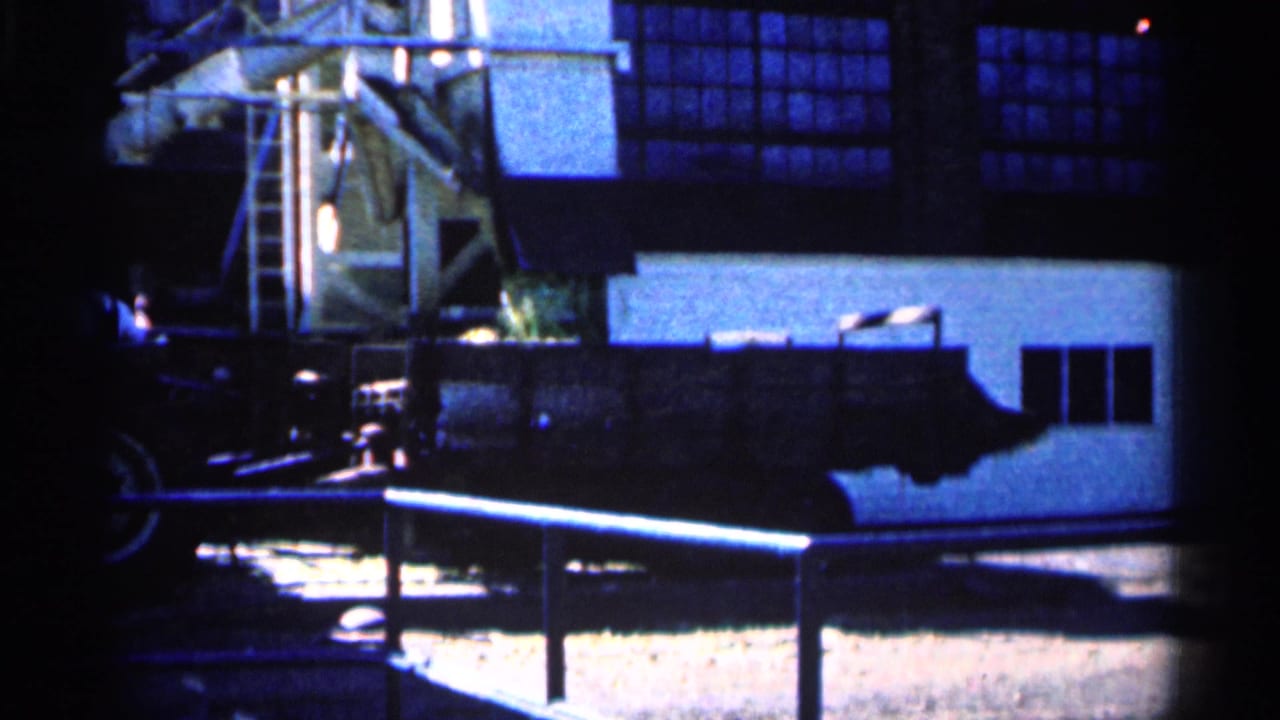 Farm structure and machinery seen in dark, grainy 8mm footage.