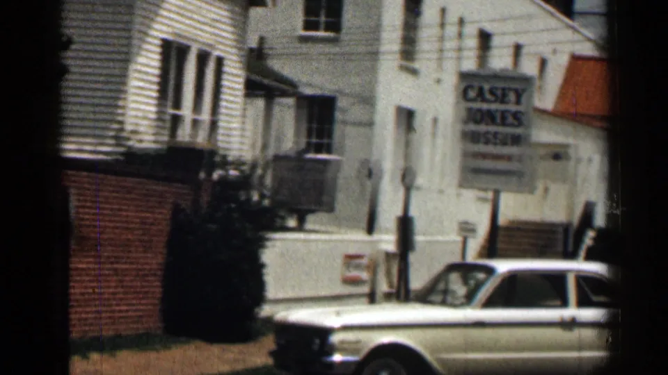 1963 Texas frame showing the Casey Jones Museum sign by a white building, with a white sedan in the foreground.
