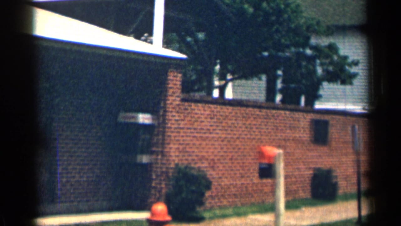 Brick building corner with a red fire hydrant and nearby houses.
