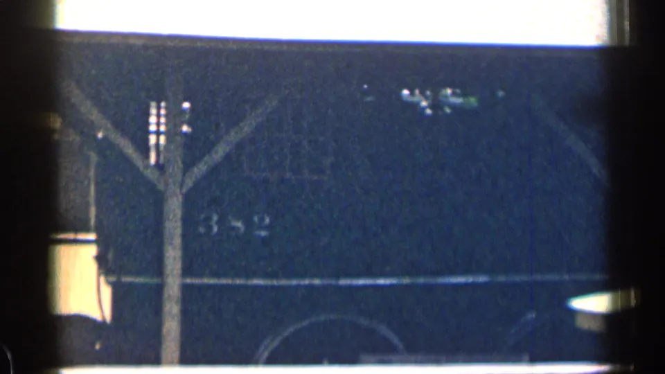 The dark train car side shows a faint 382 marking in this 1963 Texas home-movie frame, with a ledge and structural post in front.