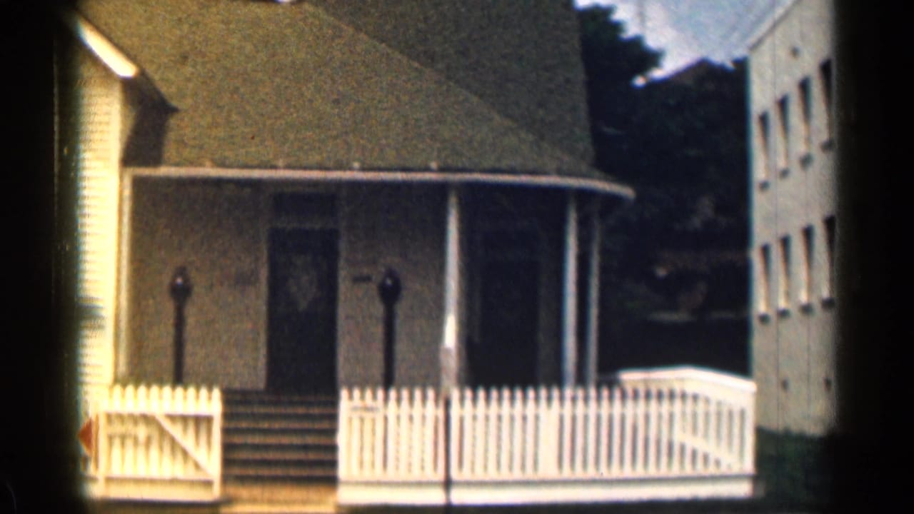 House porch and fence with a neighboring building visible at the right edge.