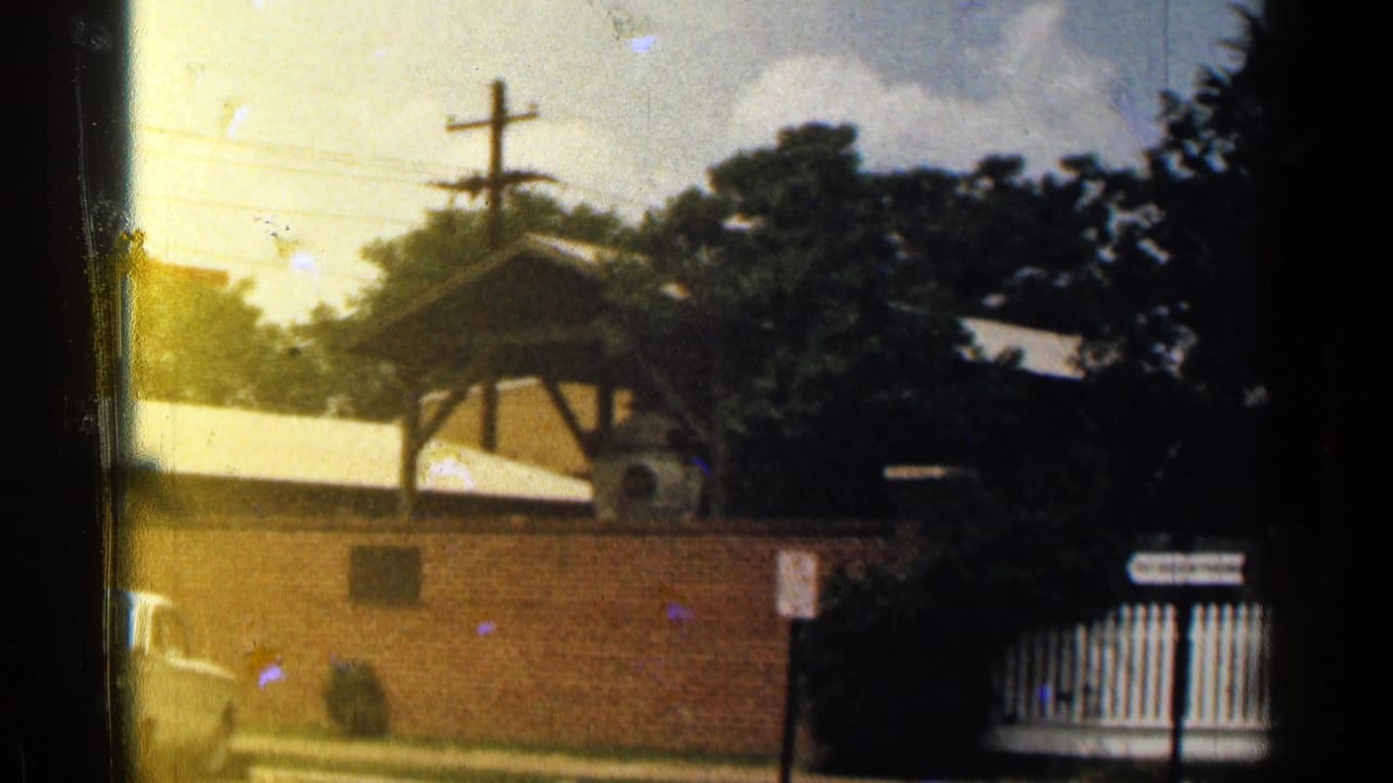 Brick wall, covered structure, trees, and roadside signs.