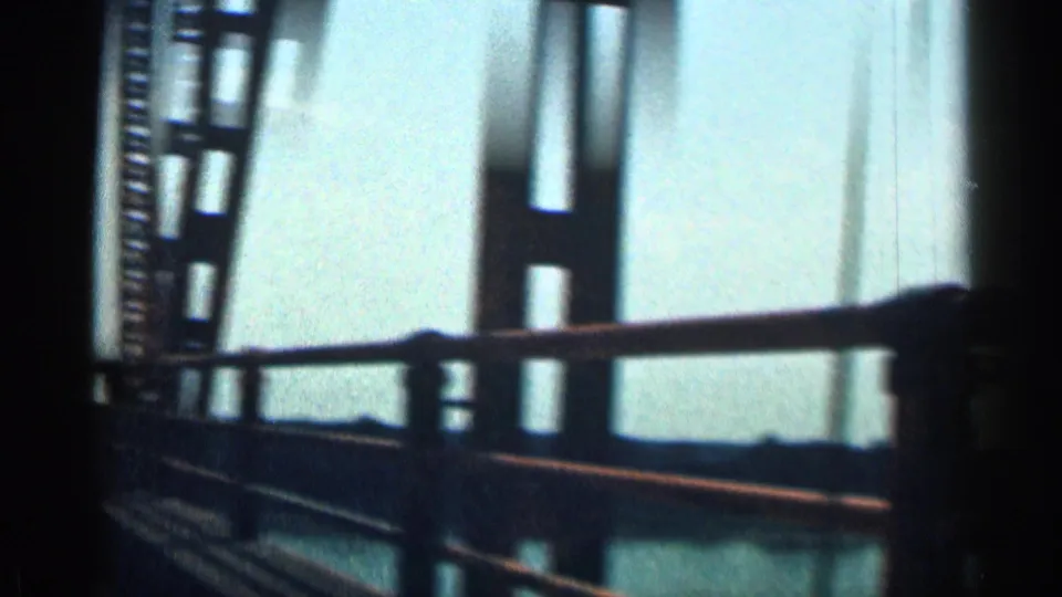 1963 Texas road-travel frame showing bridge railings and truss beams passing close to the moving camera.