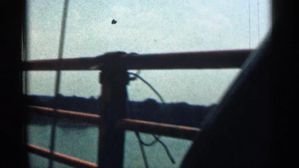 1963 Texas home-movie view through a vehicle window, with bridge rails crossing a wide river and low shoreline beyond.