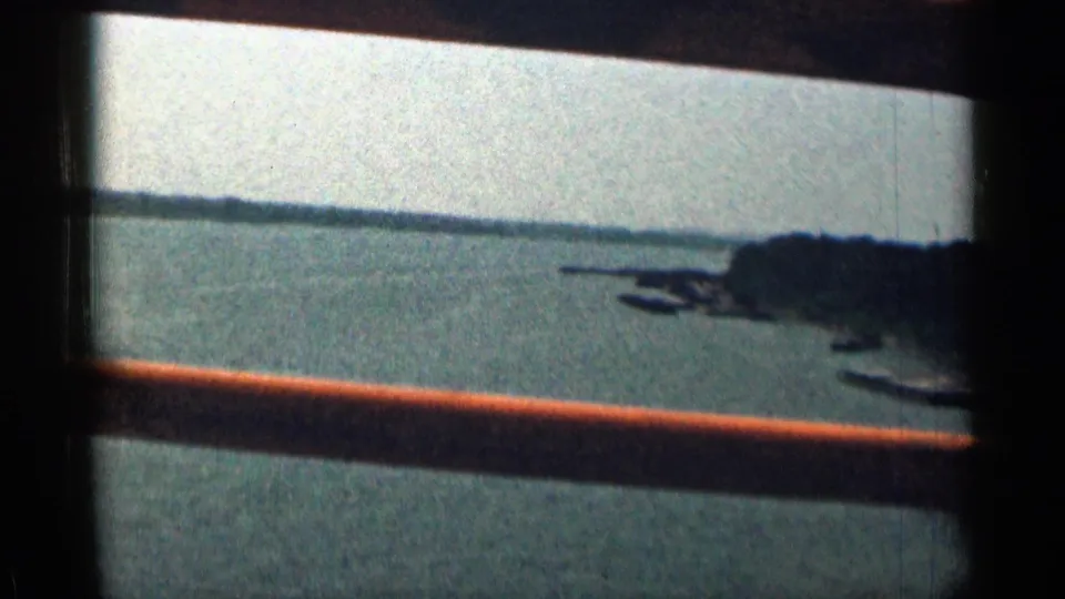 Vehicle-window view across a Texas river, with bridge rails in the foreground and a low bank or shoreline at right.