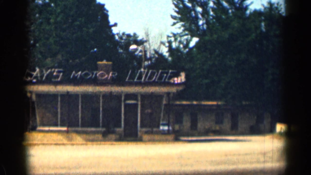Lay's Motor Lodge facade with sign above the front windows and trees behind.