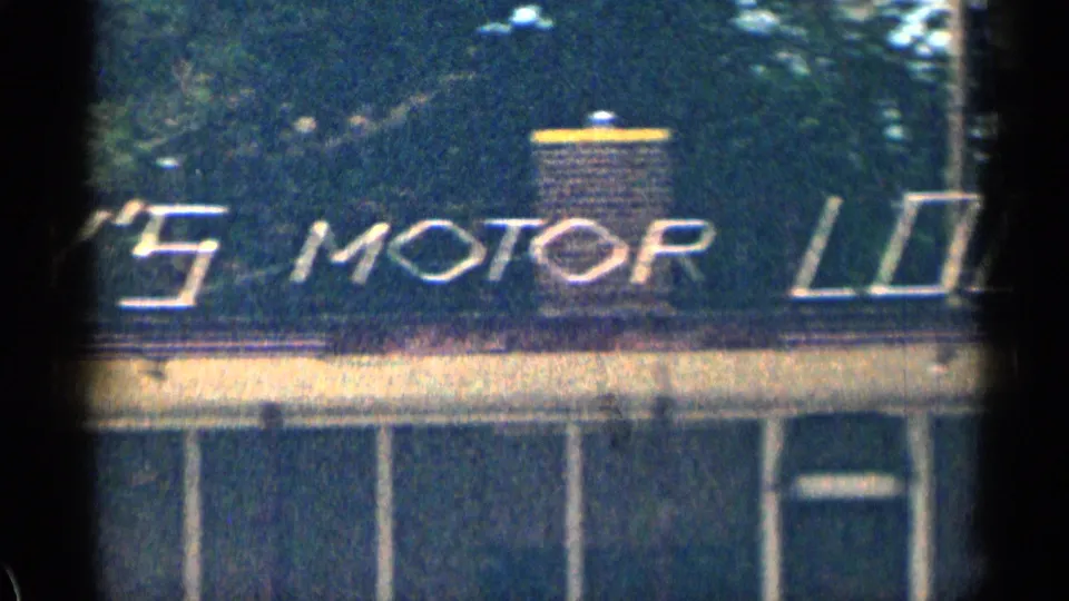 1963 Texas frame with the visible Lay's Motor Lodge sign stretching across a roadside motel roofline, with windows and railing below.