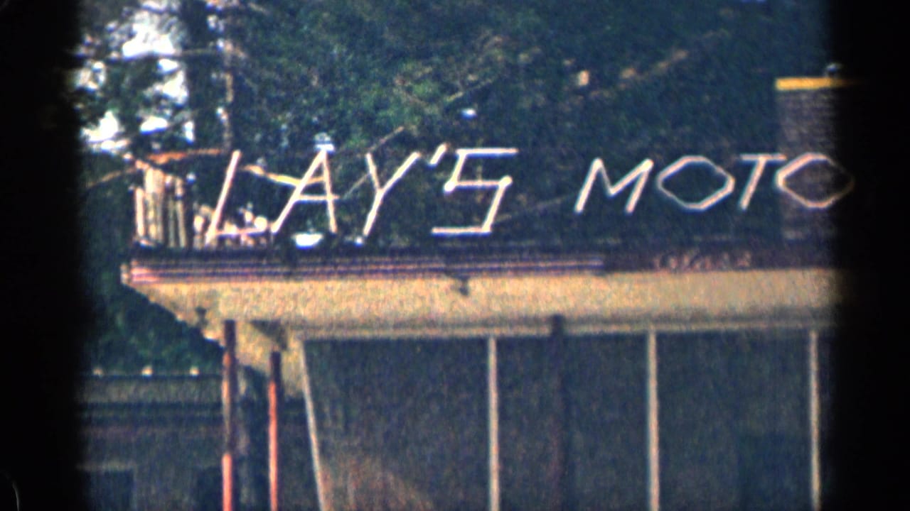 Lay's Motor sign on a building roof, framed through dark 8mm film edges.