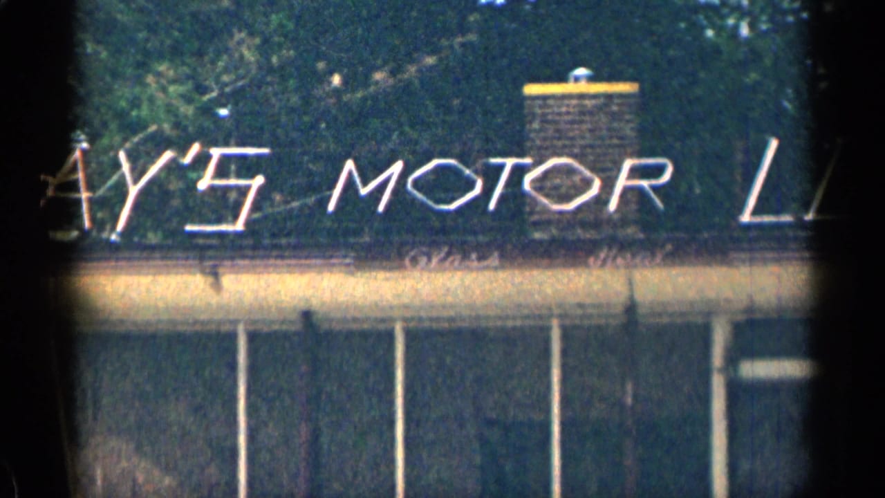 Partial Lay's Motor sign repeated across a building roof with trees behind.