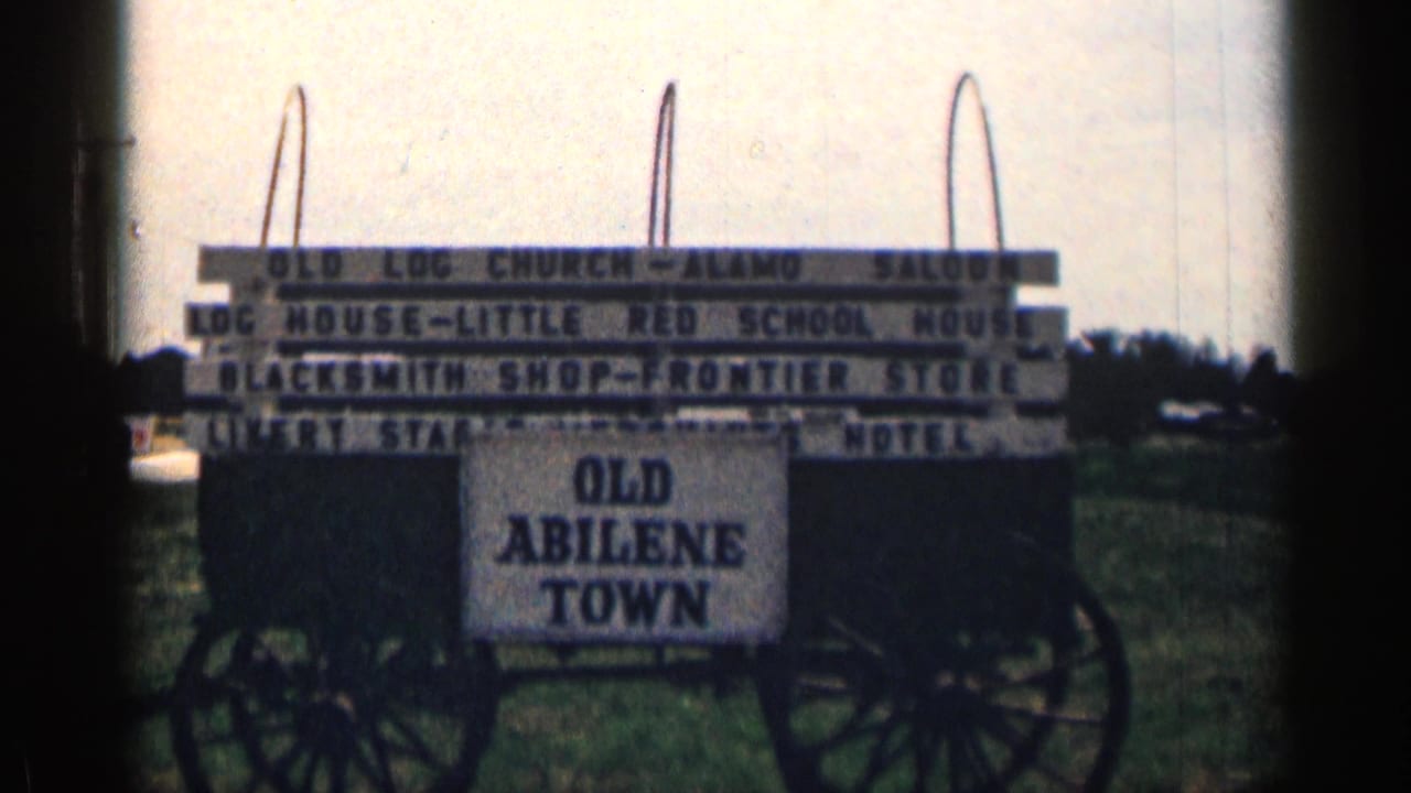 1963 Texas home-movie frame showing the Old Abilene Town wagon sign with attraction boards and soft 8mm exposure.