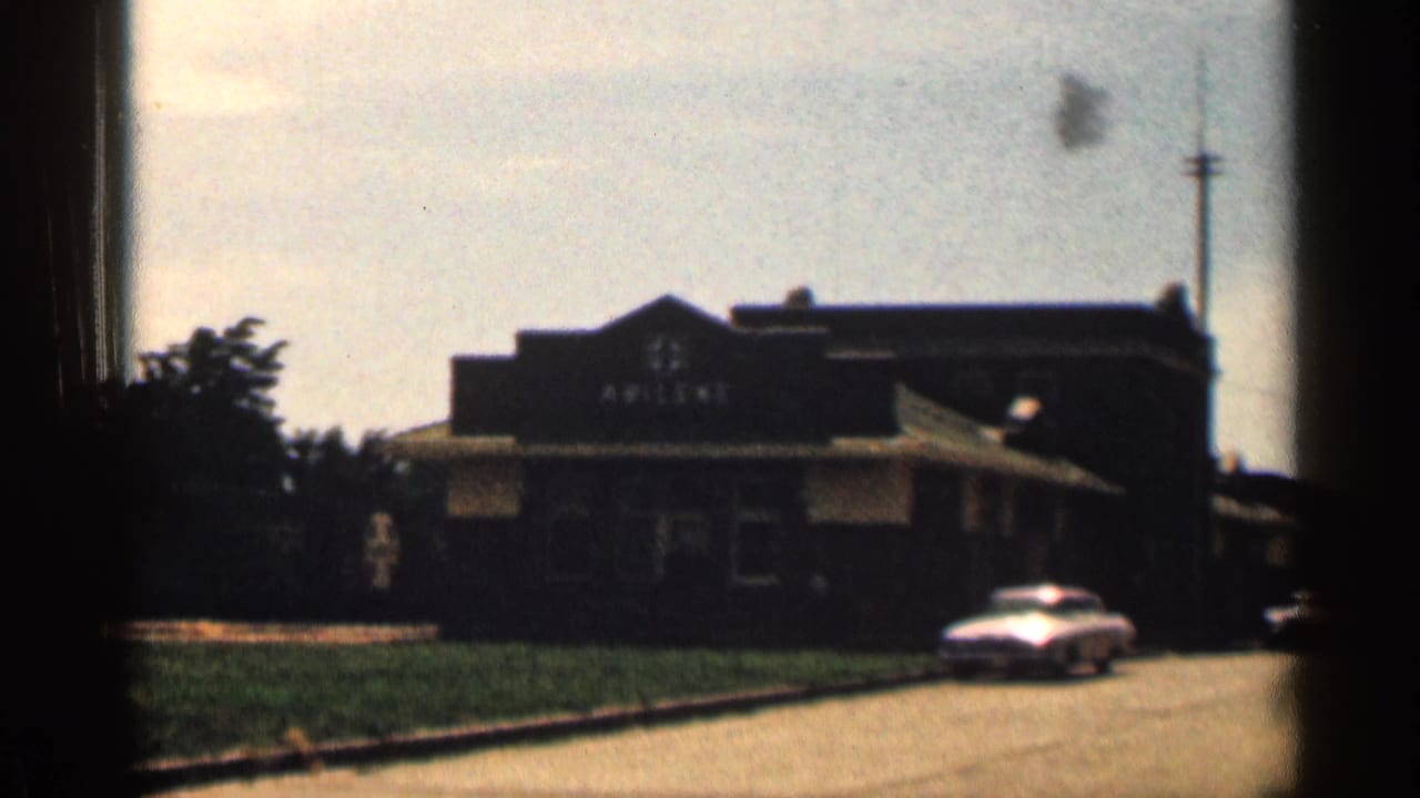 Dark roadside building with ABILENE sign and a classic car near the curb.