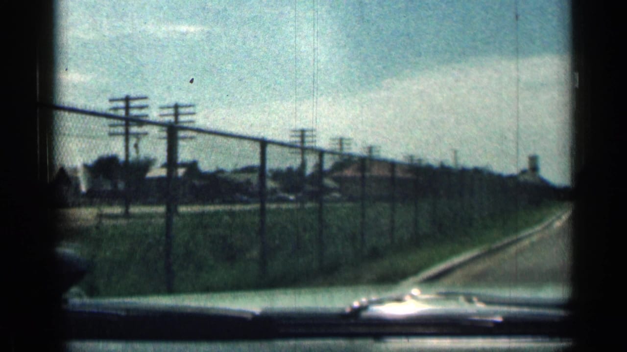 Roadside chain-link fence seen through a car windshield.